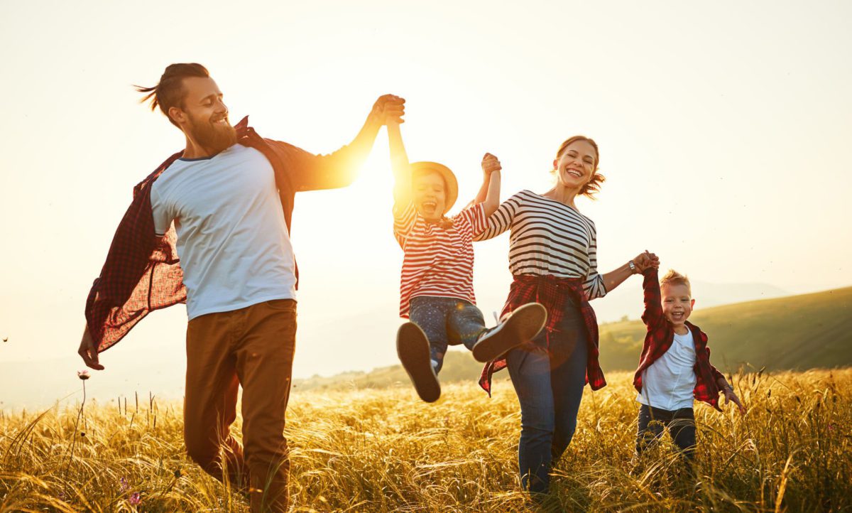 Family running together through a sunny field holding hands