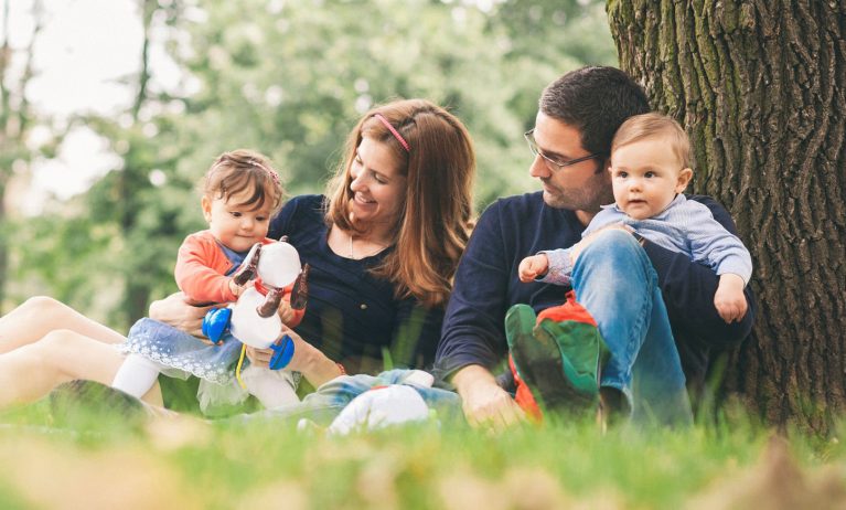 Family relaxing outdoors on grass with children