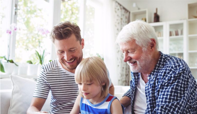 Grandfather and father spending time with a young child at home